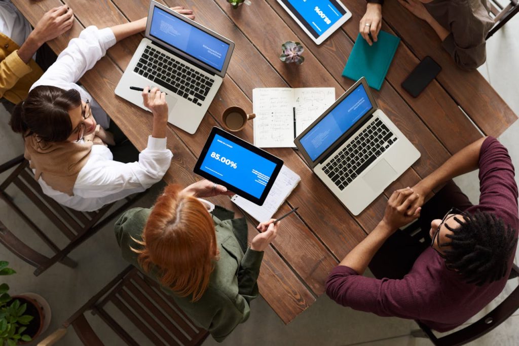 pexels-image-3182773 Top View Photo of Group of People Using Macbook While Discussing